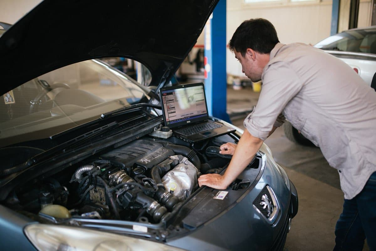 Mecânico com notebook conectado ao carro fazendo diagnóstico eletrônico
